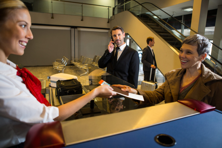 Female staff giving boarding pass to the passenger at the airport terminal